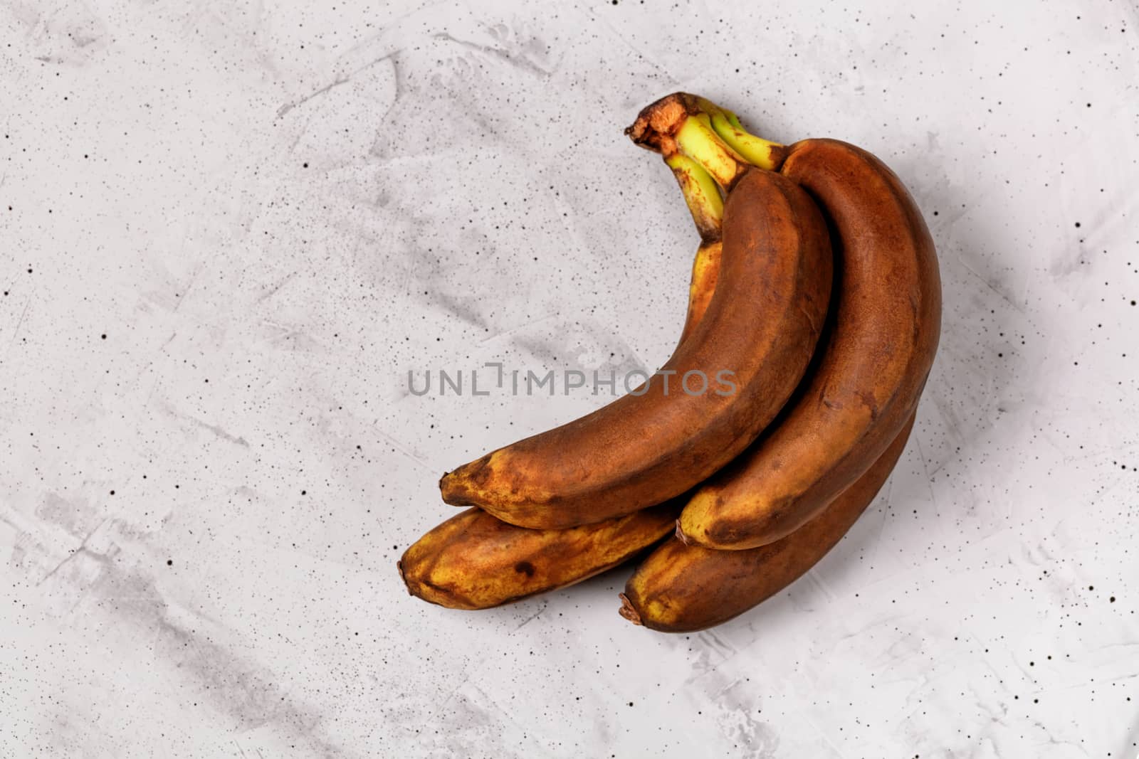 Ugly brown ripe bananas on a gray concrete background, flat lay, image with copy space.