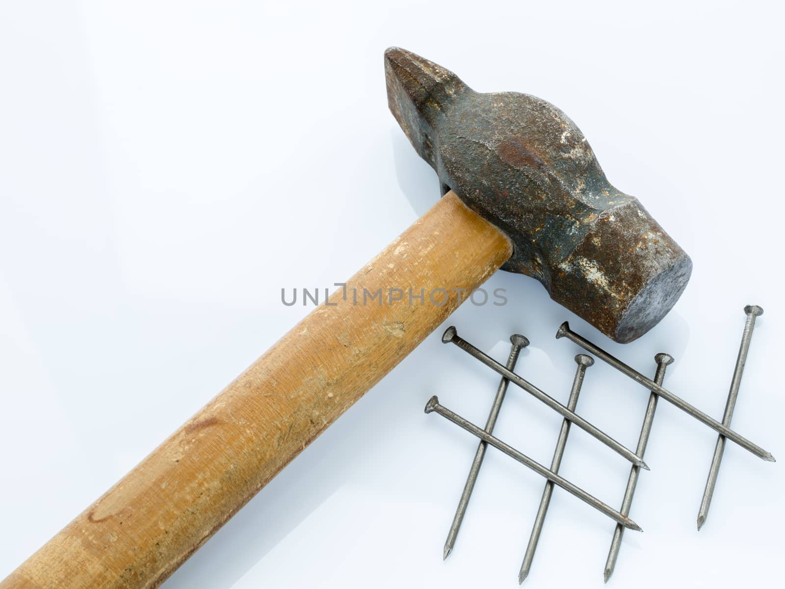 An old hammer with a wooden handle and a bunch of nails. Objects on a light background