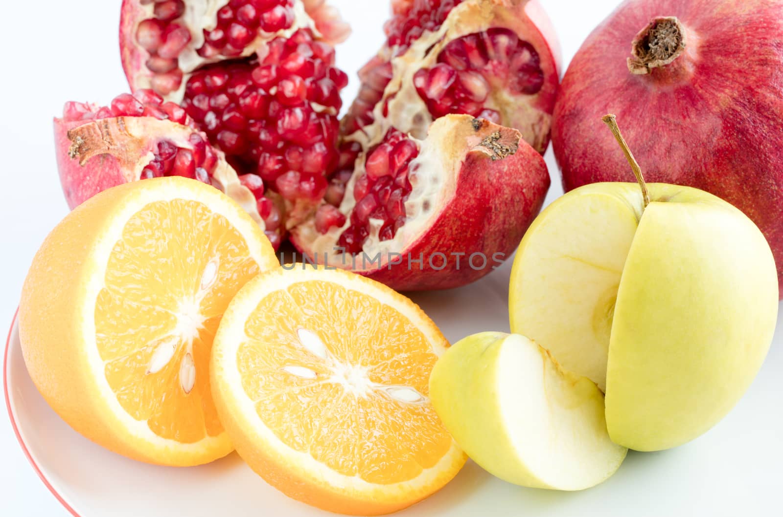 Ripe fruit: pomegranate, orange, apple, sliced on a white background close-ups 