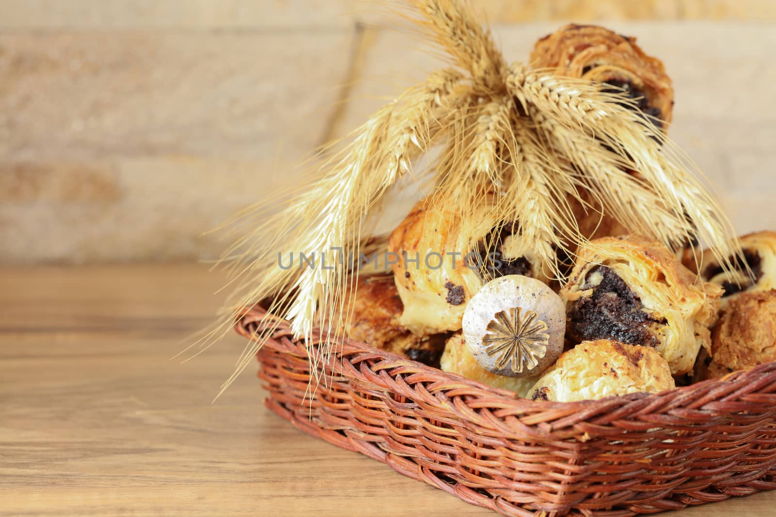 Sweet rolls with poppy seeds lie in a wicker basket by Sergii