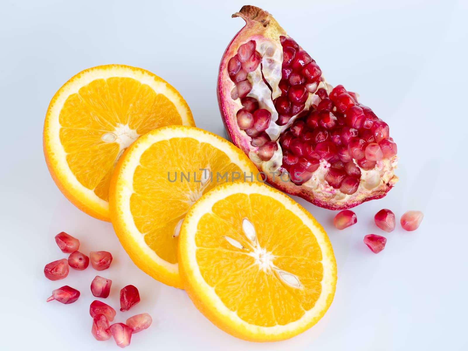 Sliced orange and pomegranate on a light blue background by Sergii