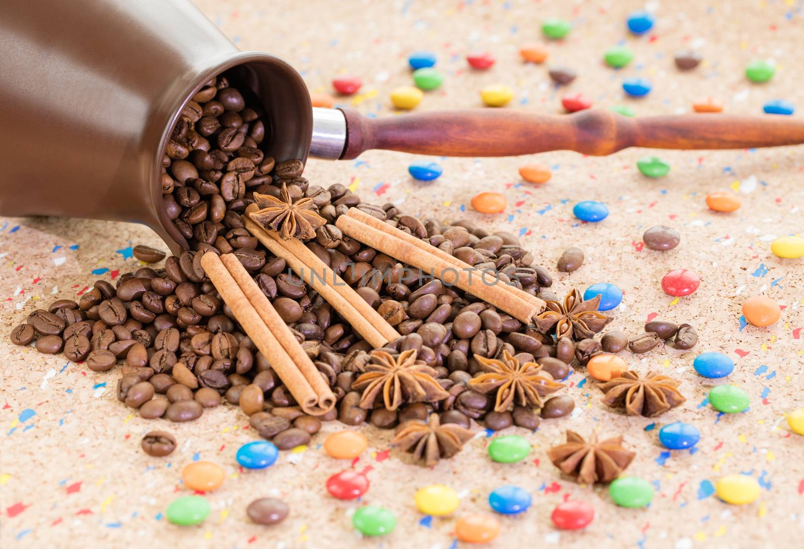 A tumbled clay jezva jar filled with coffee beans, anise and cinnamon sticks with colorful candies