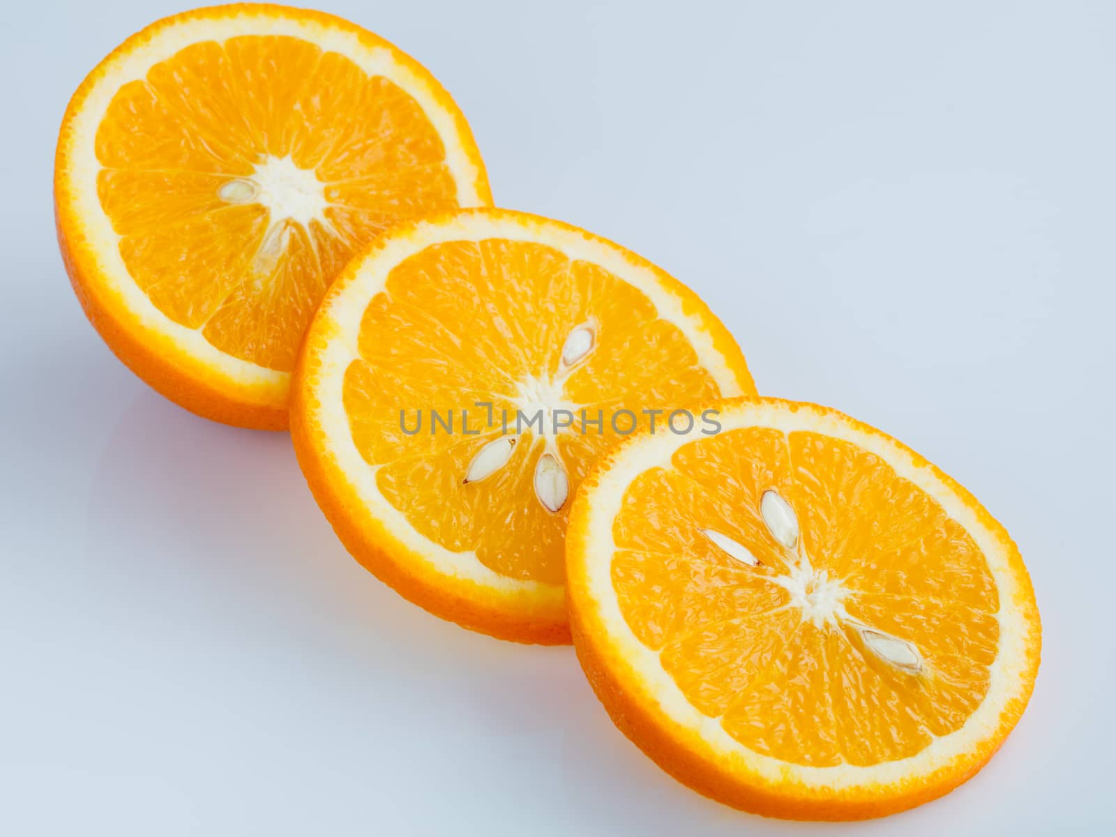 Three rings of sliced juicy ripe orange on a light blue background.