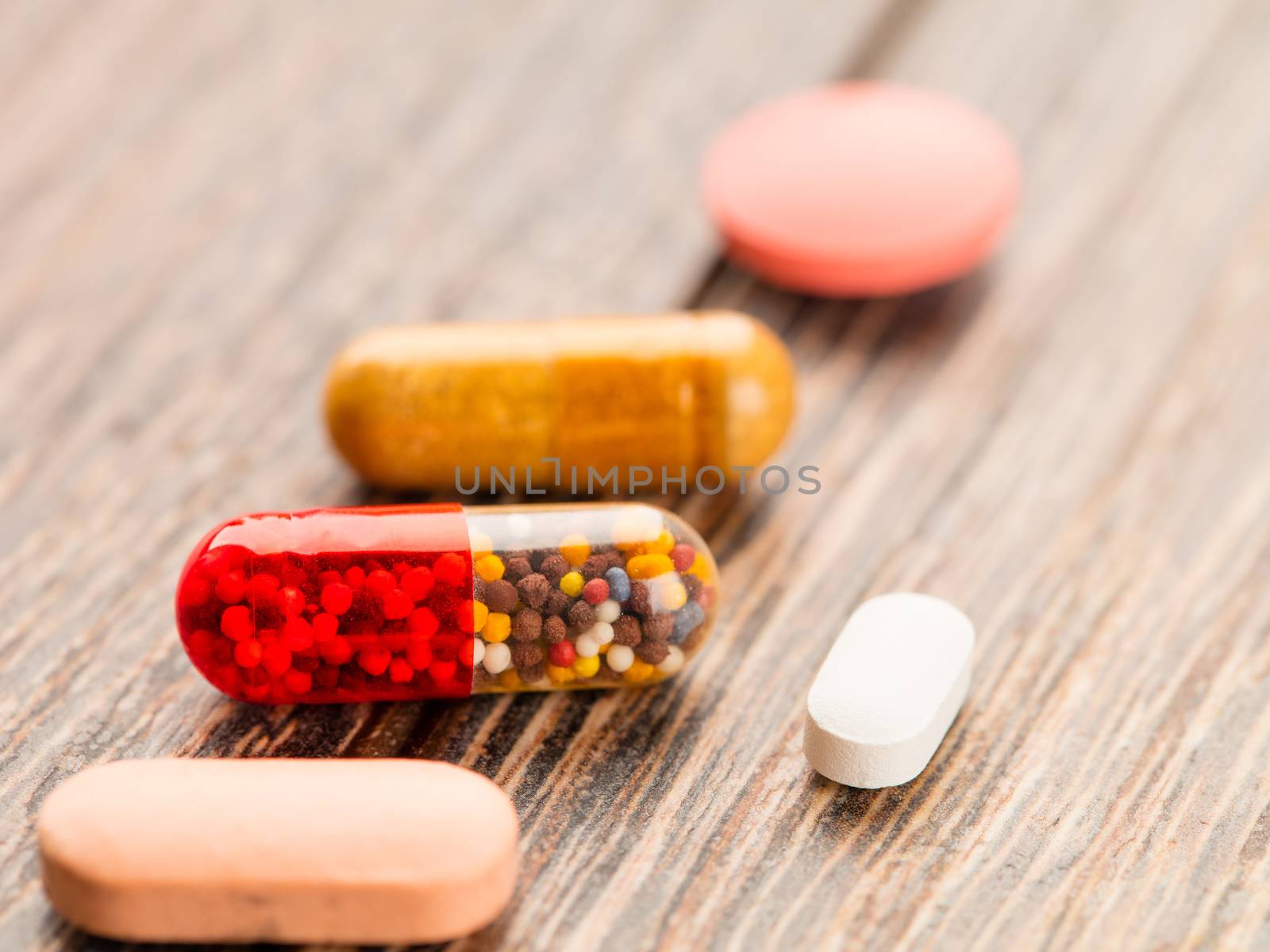 Tablets and capsules in a lid on a wooden table