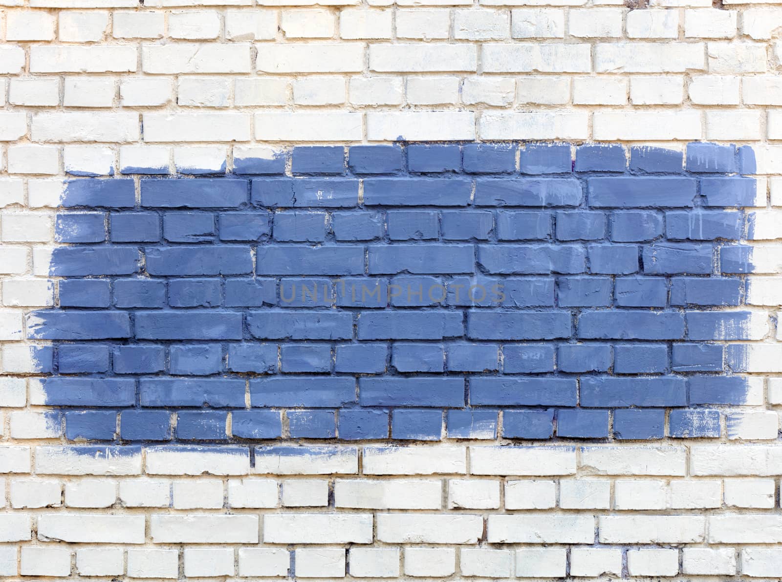 On the white old brick wall the selected fragment is painted with blue paint. by Sergii