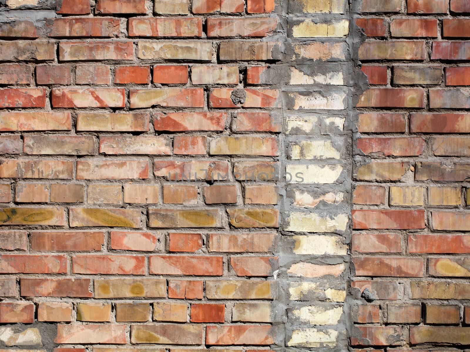 On an old wall of red bricks a separated vertical fragment of the old silicate brick by Sergii