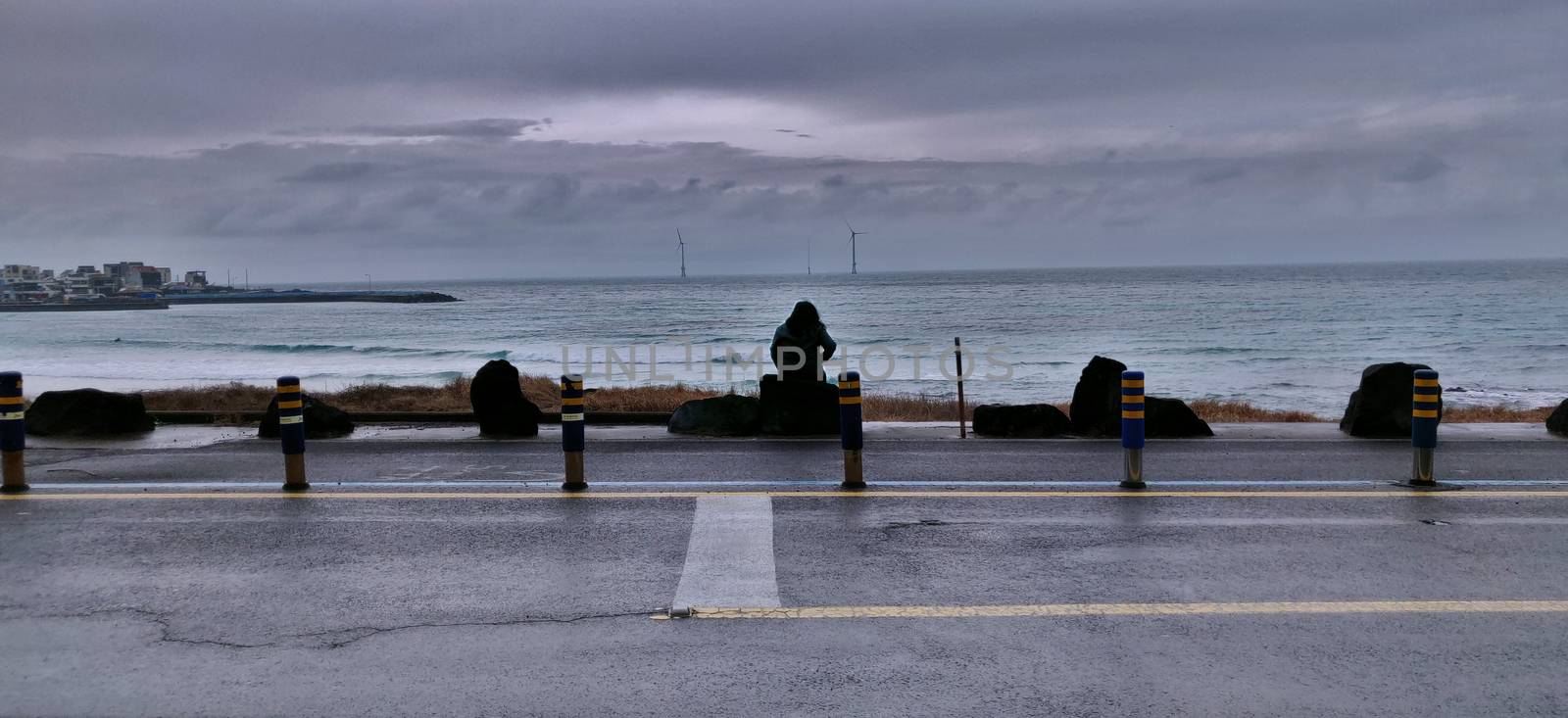 A woman overlooking the sea alone in Woljeongri beach in jeju island, south korea