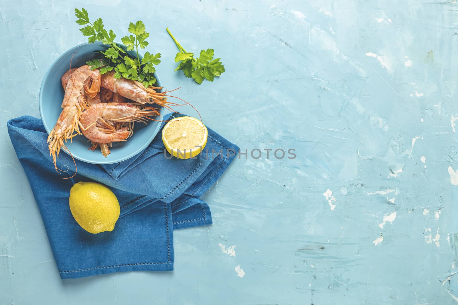 Shrimp, prawn with parsley in blue ceramic plate surrounded napk by ArtSvitlyna