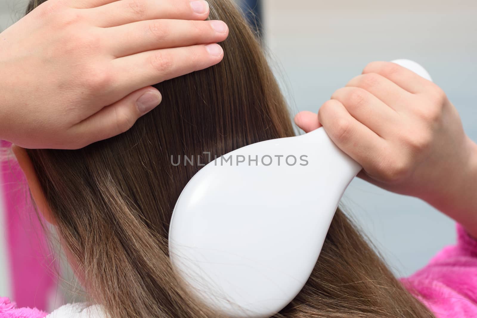 Teenager's hand combing long hair, close up by Madhourse