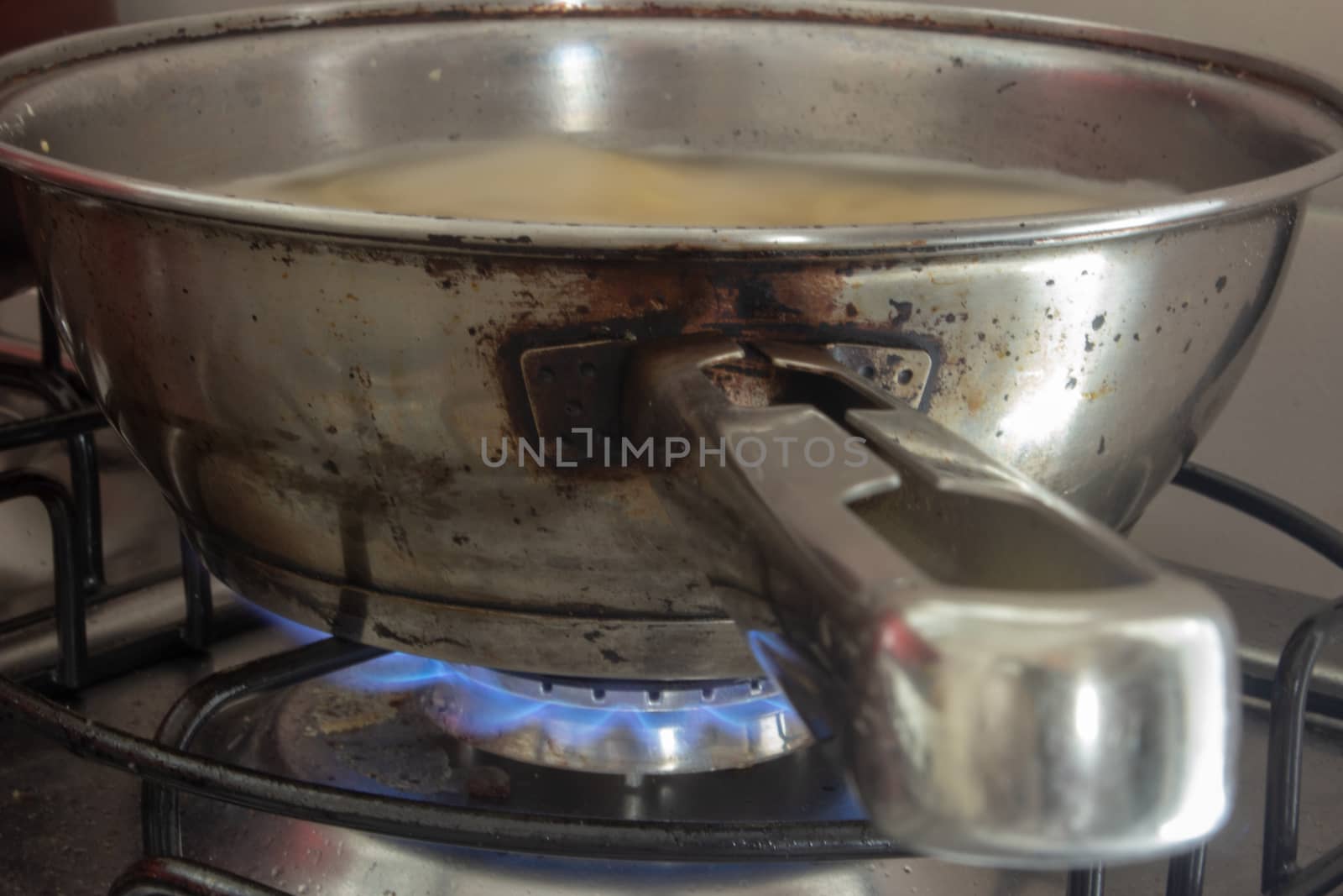 Iron pan boiling some water with pasta on a stove with the fire on