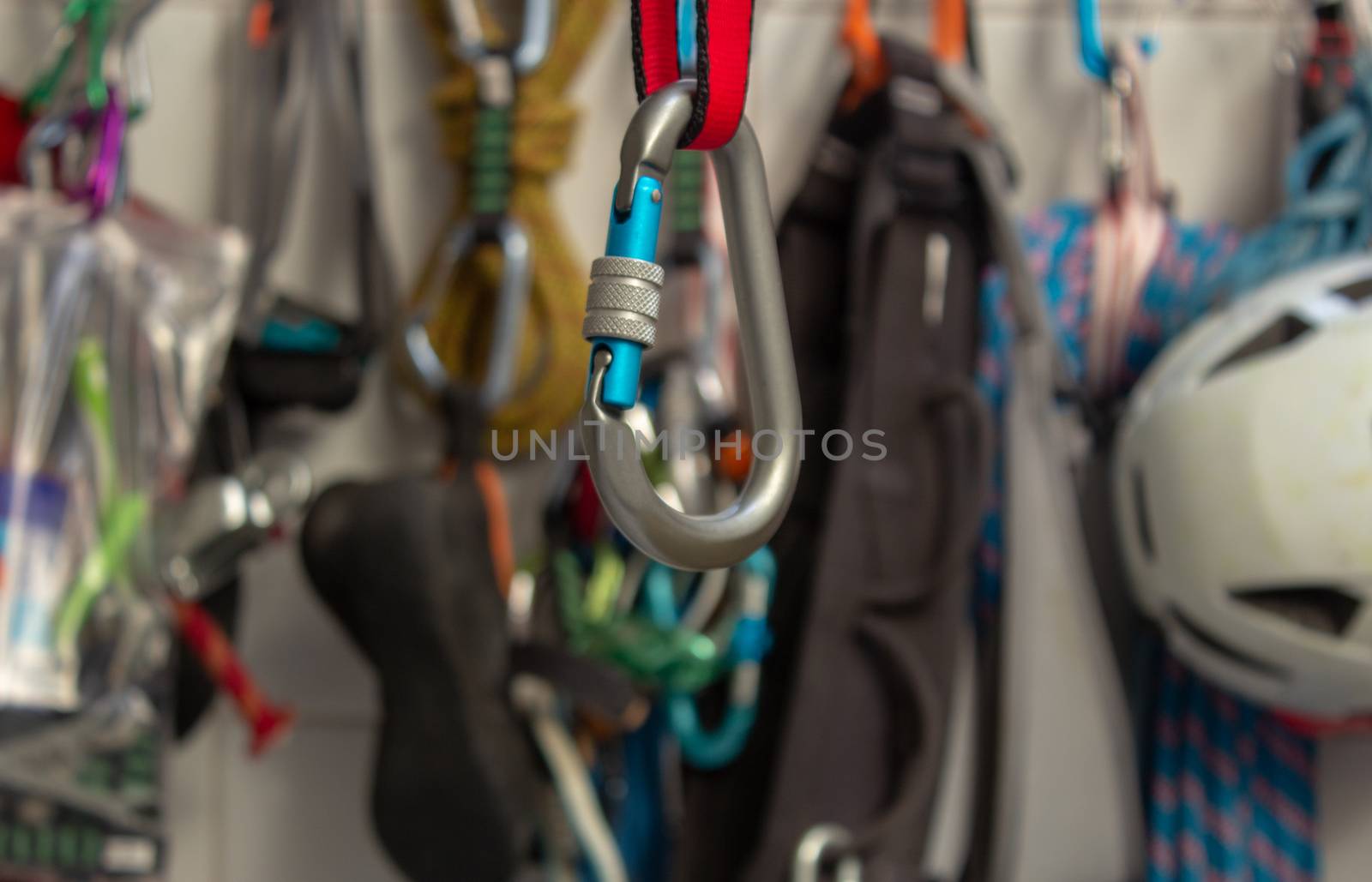 Screwgate carabiner attached to a nylon sling with a bunch of climbing gears on the background