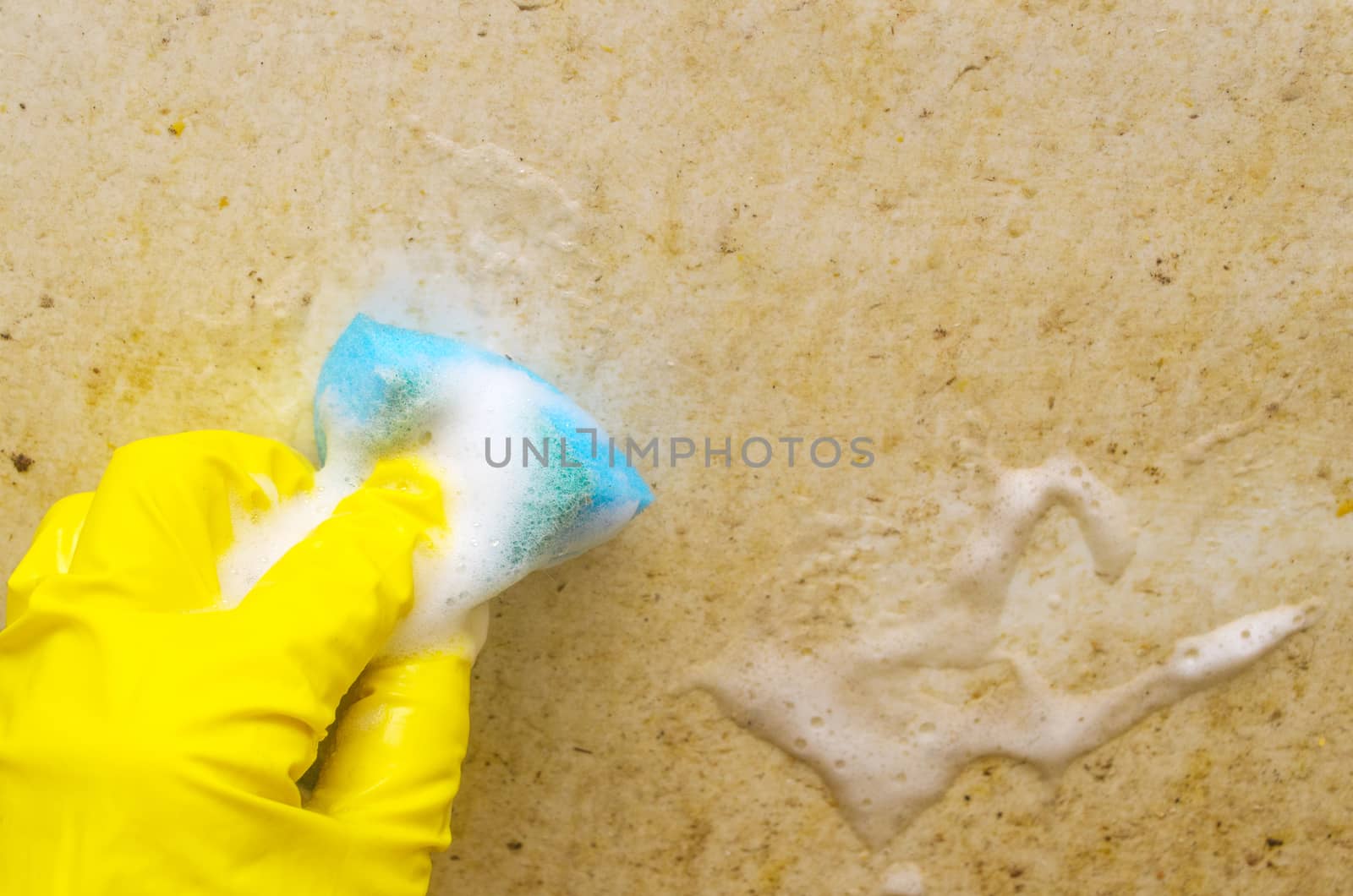 A man in a yellow protective glove washes a very dirty bath with a blue sponge..Regular domestic cleaning in bathroom. by andre_dechapelle