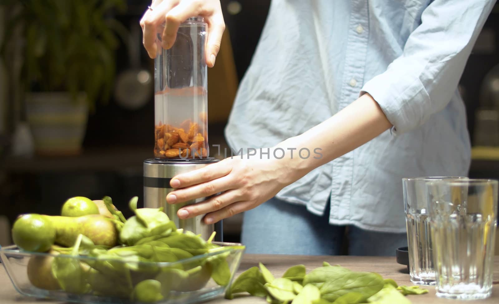 Cooking of almond milk. Woman sets a blender glass on a blender and presses a button. Healthy eating concept