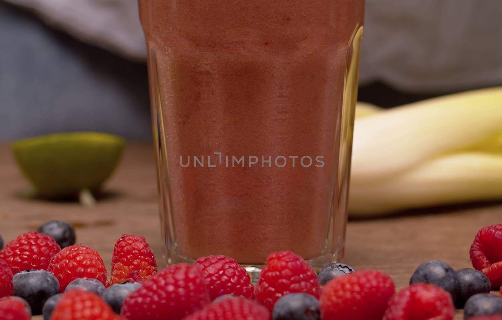 Close up glass of ready made smoothies and celery, raspberries, blueberrieson the table. Fresh healthy food.