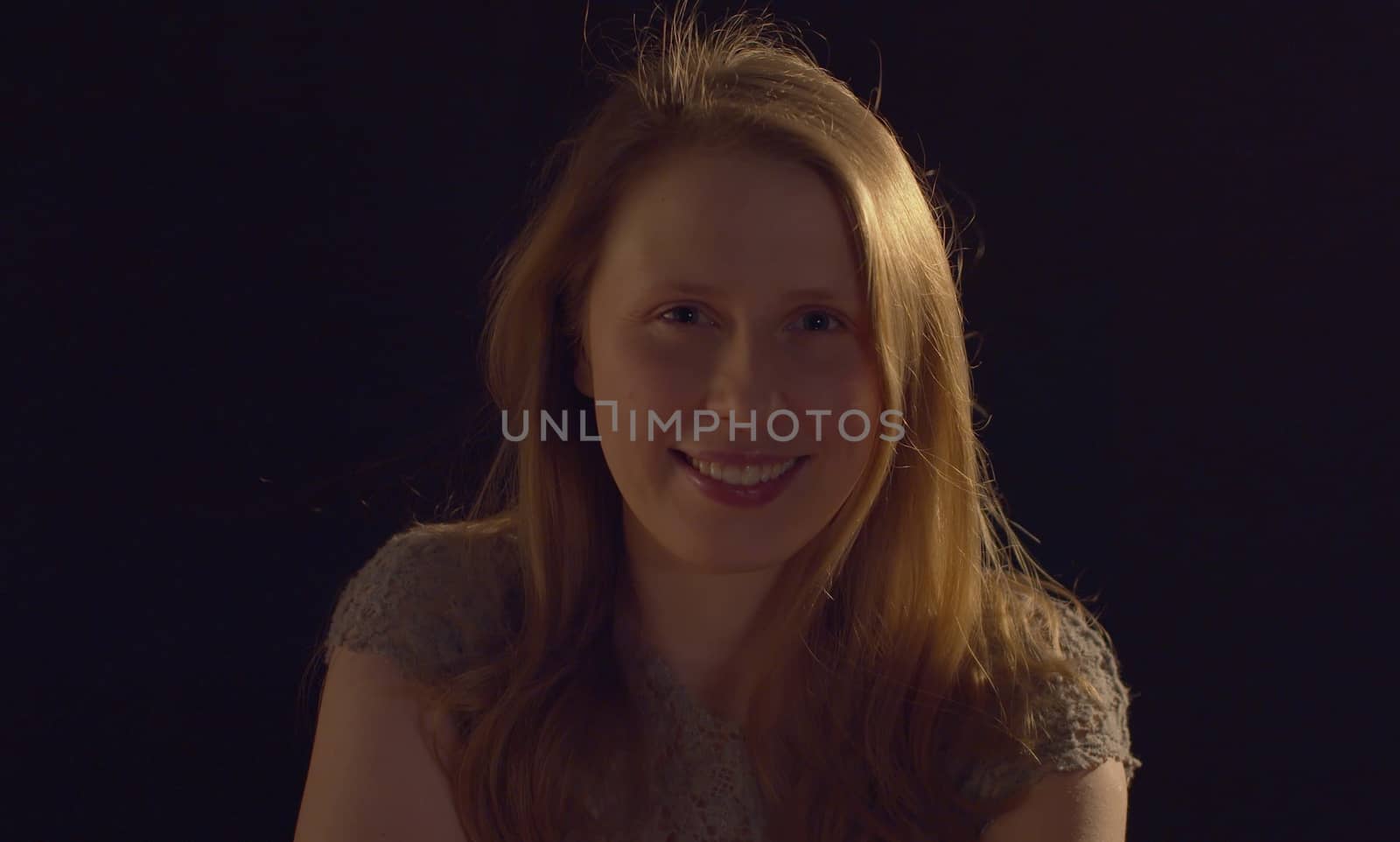 Close up portrait of a young smiling woman on a dark background. Pretty caucasian lady front view