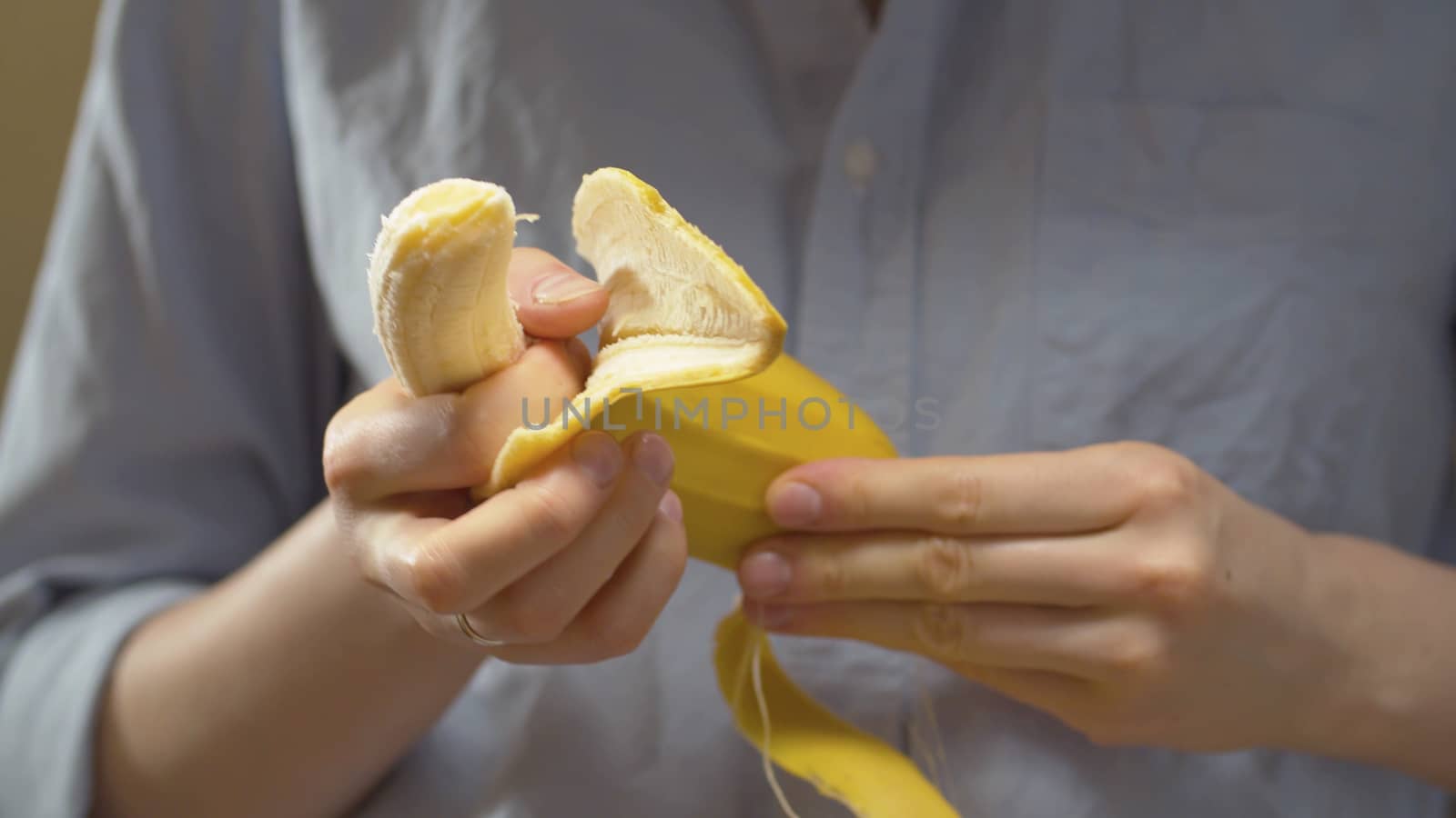 Close up female hands peeling a banana. Healthy lifestyle and eating concept