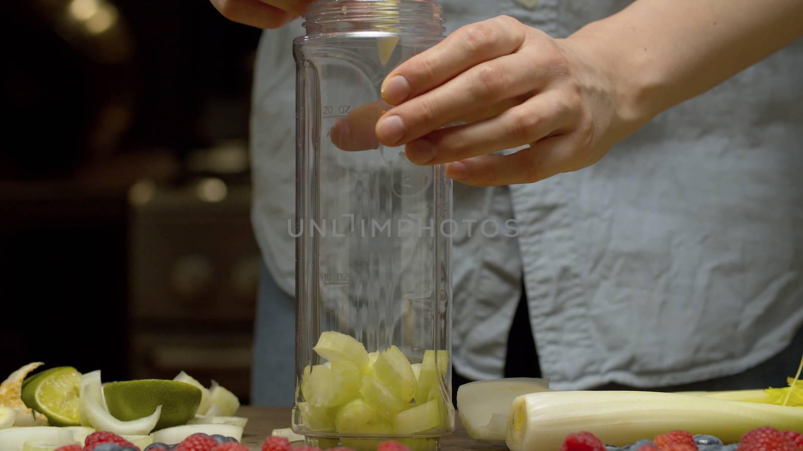 Close up woman's hands putting chopped celery stalk in a blender glass. Preparing smoothies closeup. Fresh healthy food