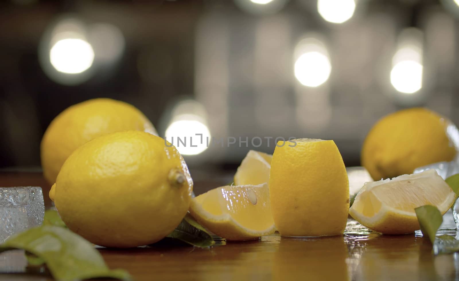 Close up lemon on the table over background of blurry light bulbs. Bar counter closeup