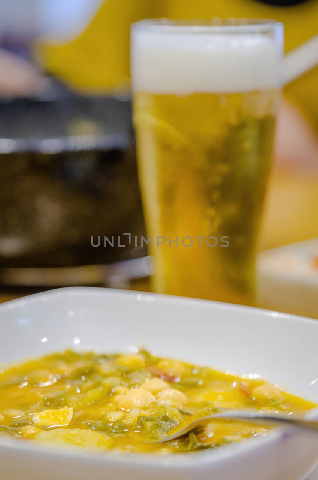 White plate of bean stew. Home-cooked food. Accompanied by cold beer. Restaurant menu of the day