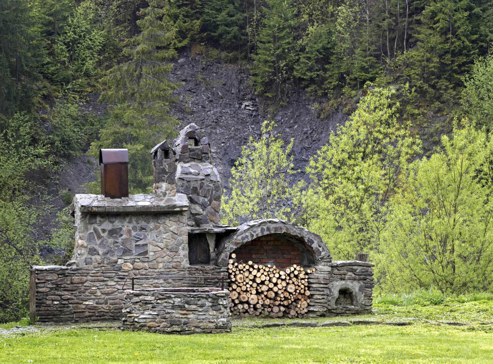 An old stone stove with firewood, a skewer for meat and a smokehouse for cooking outdoors in the Carpathians.