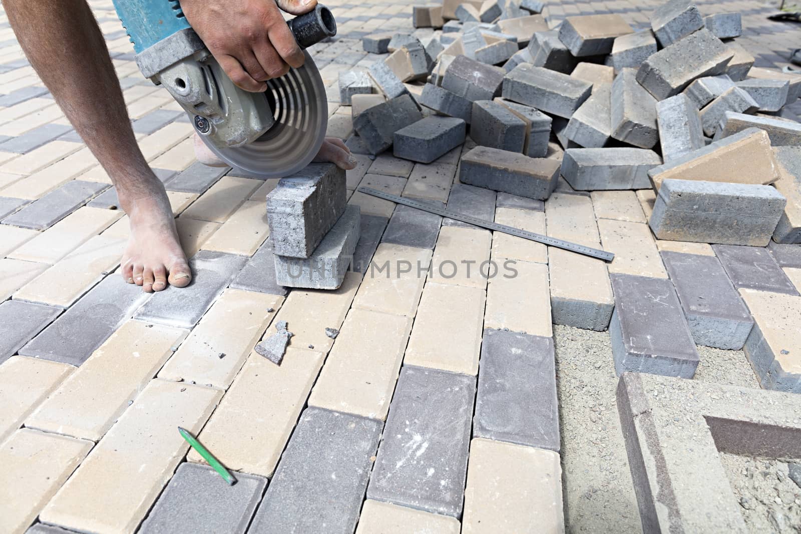 The worker cuts a bar of paving slabs for the final laying on the sidewalk