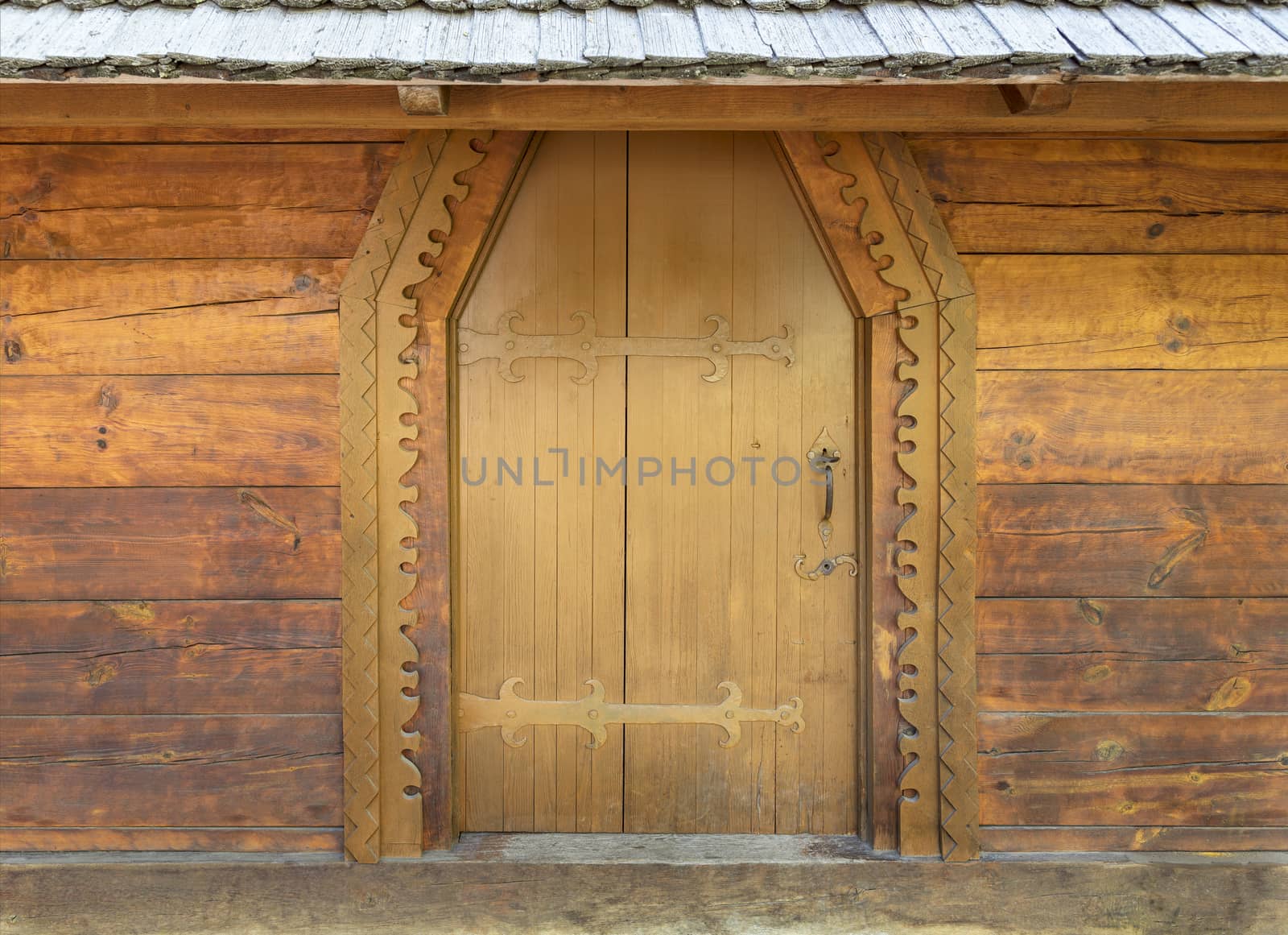 Ancient antique wooden doors of the old hut with wrought iron crossbar.