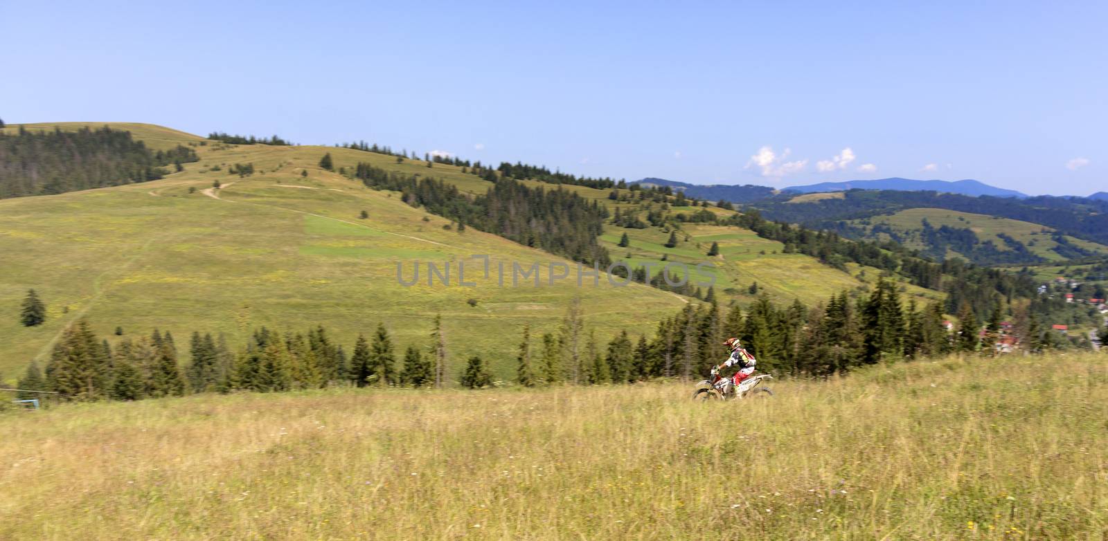 Motorcyclist moves down the slope of the Carpathian Mountains by Sergii