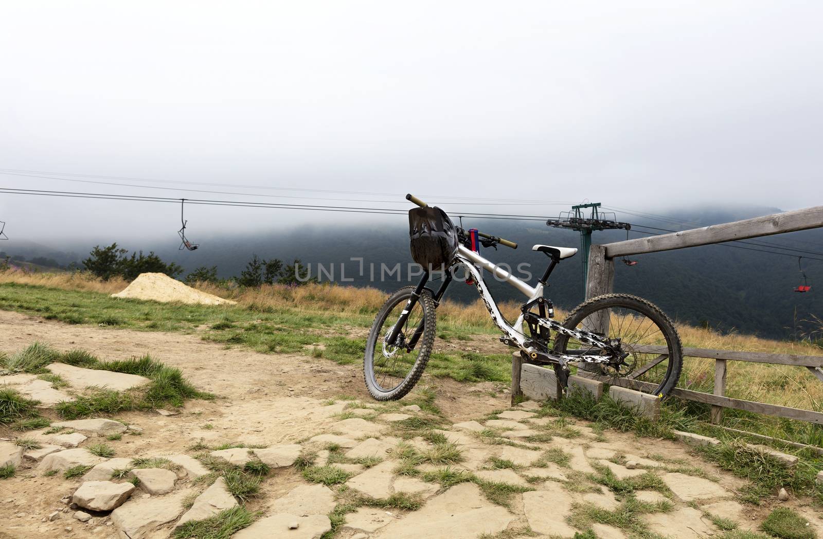 Carpathians. The cyclist left a mountain bike for a respite. The lift is in a thick fog in the background of a mountain landscape.