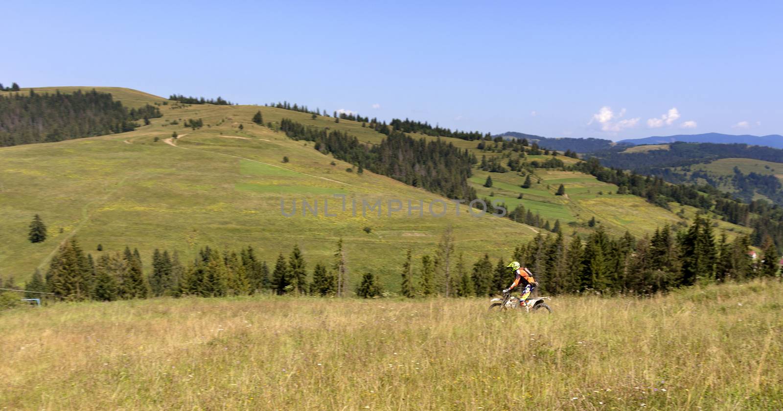 Motorcyclist moves down the slope of the Carpathian Mountains by Sergii