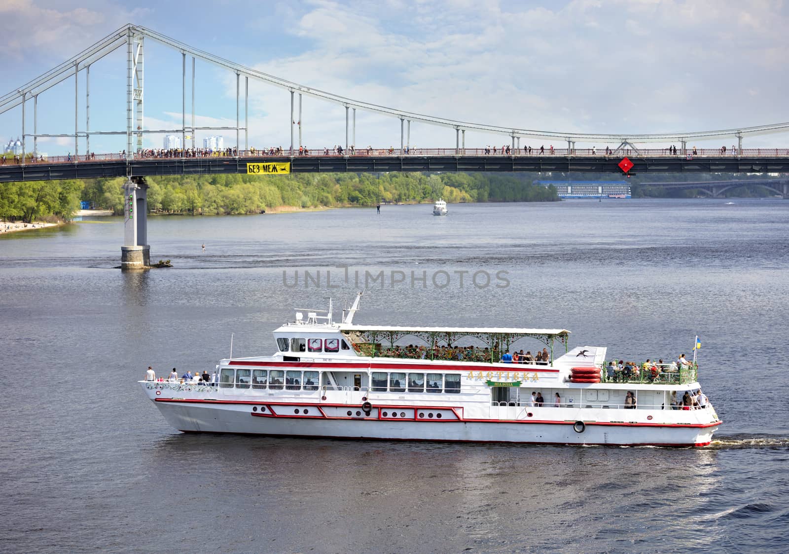 A white promenade boat carries people across the Dnieper in a bright sunny day by Sergii