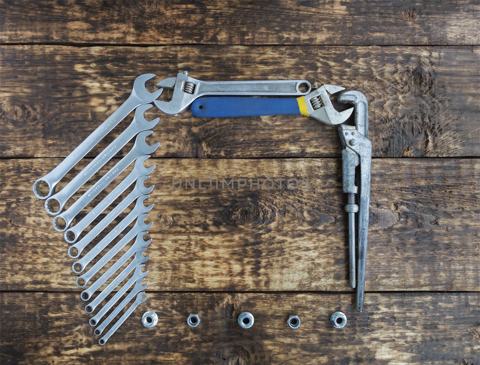 Set of combination wrenches and old adjustable wrenches on an old wooden boards background