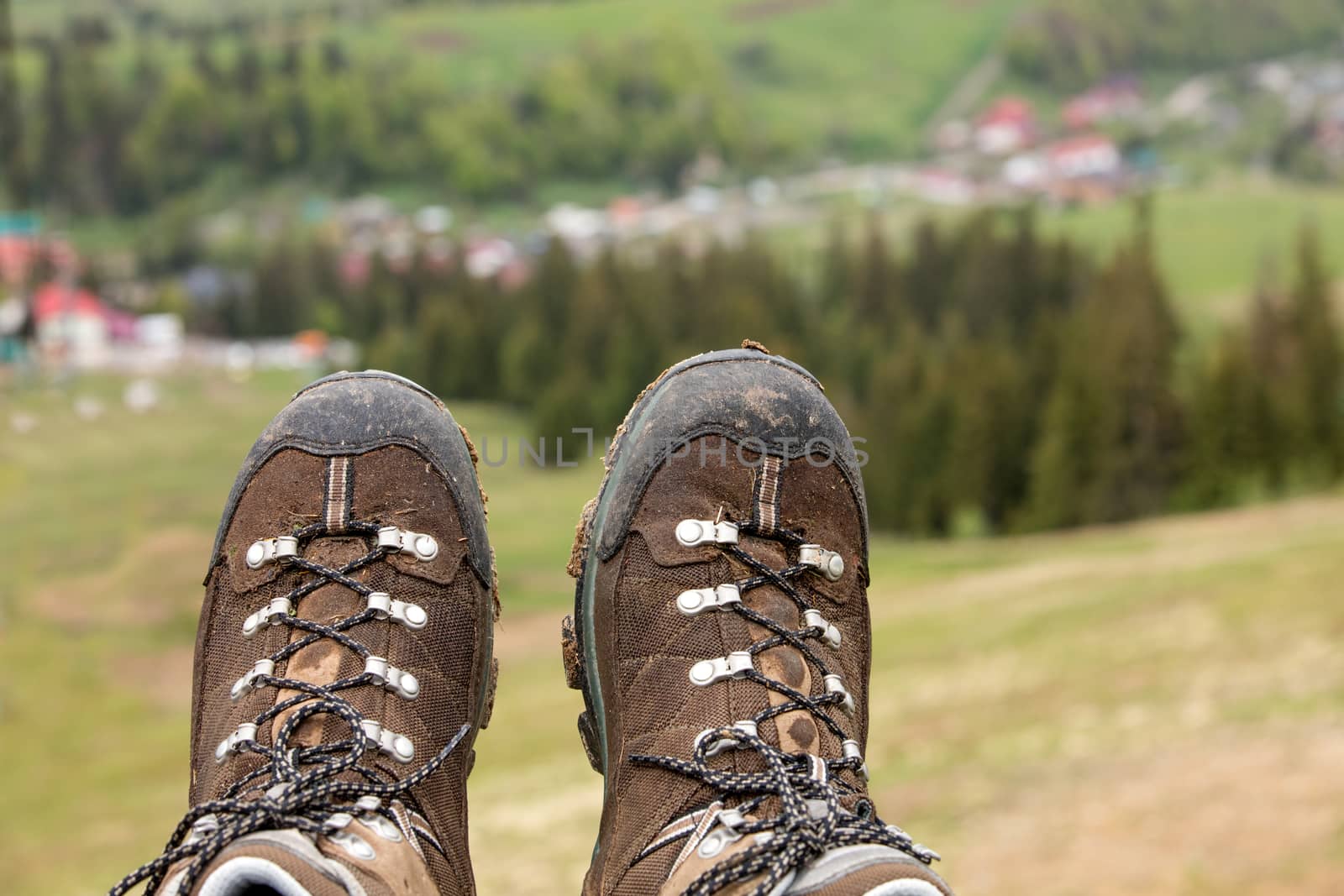 Mountain tracking boots close-up after a long trek through the mountains on a blurred green background of the valley of the summer mountains