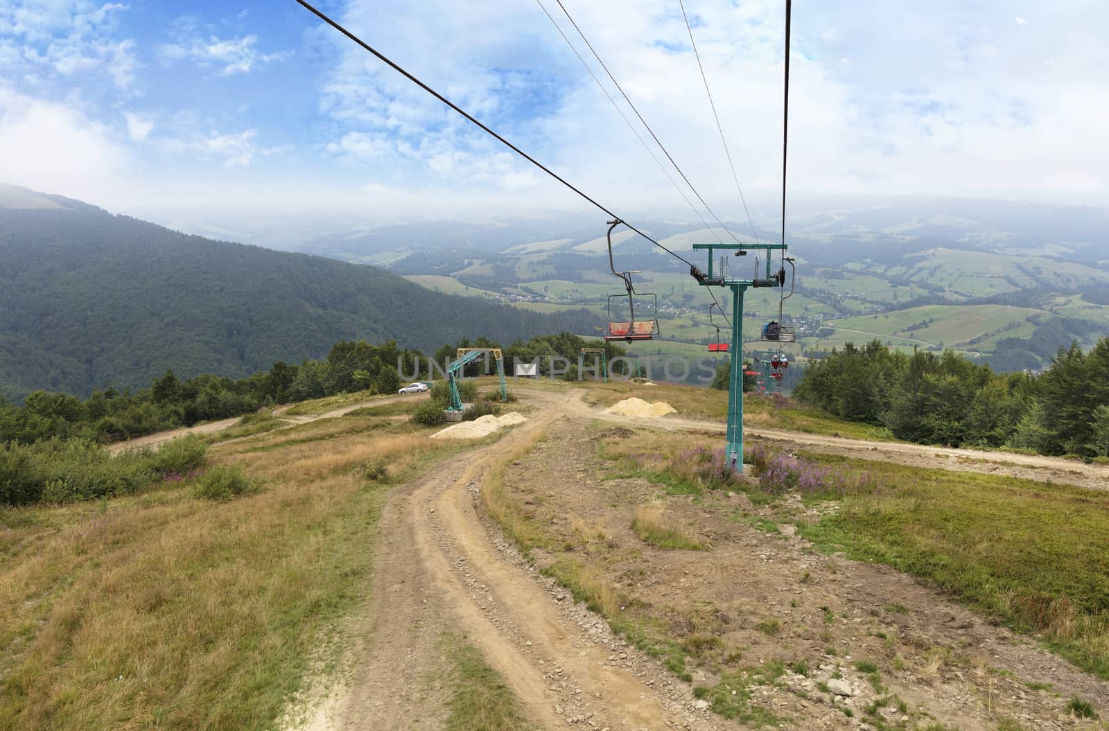 The mountain lift carries tourists and luggage up and down the mountains against the backdrop of the summer mountain scenery in the Carpathians