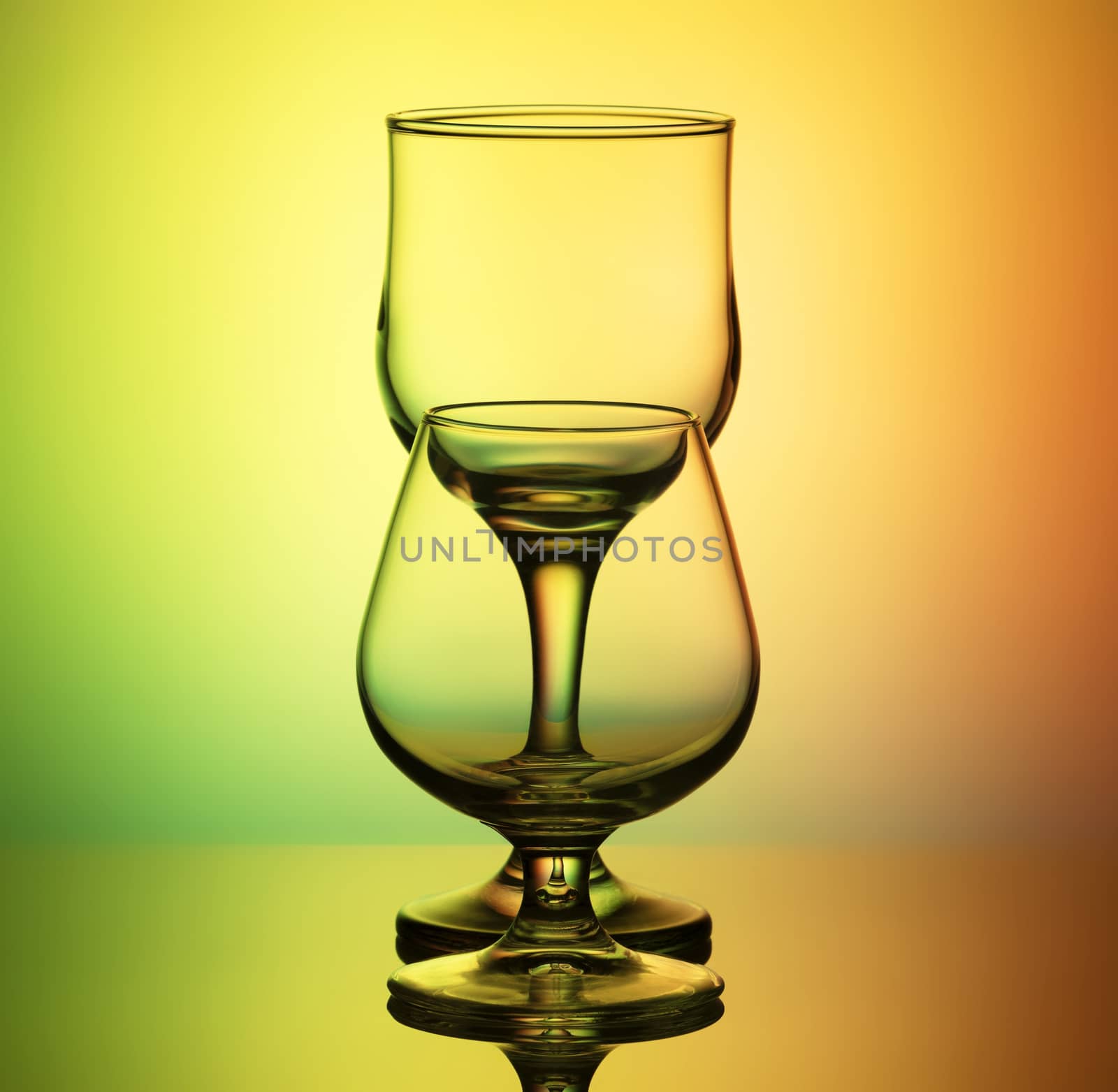 glasses for wine and cognac with a thin contour stand arches after the other, on a bright yellow-green background