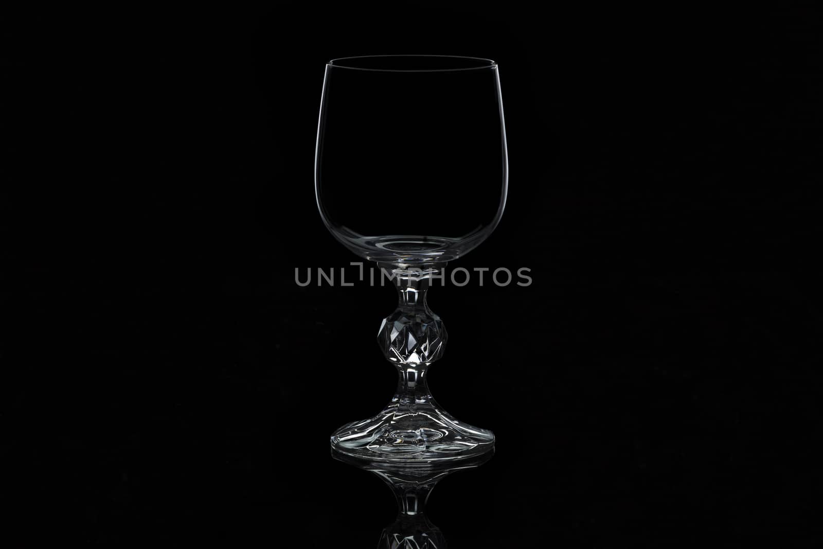 glass for wine with a thin contour and curly leg, isolated on a black background
