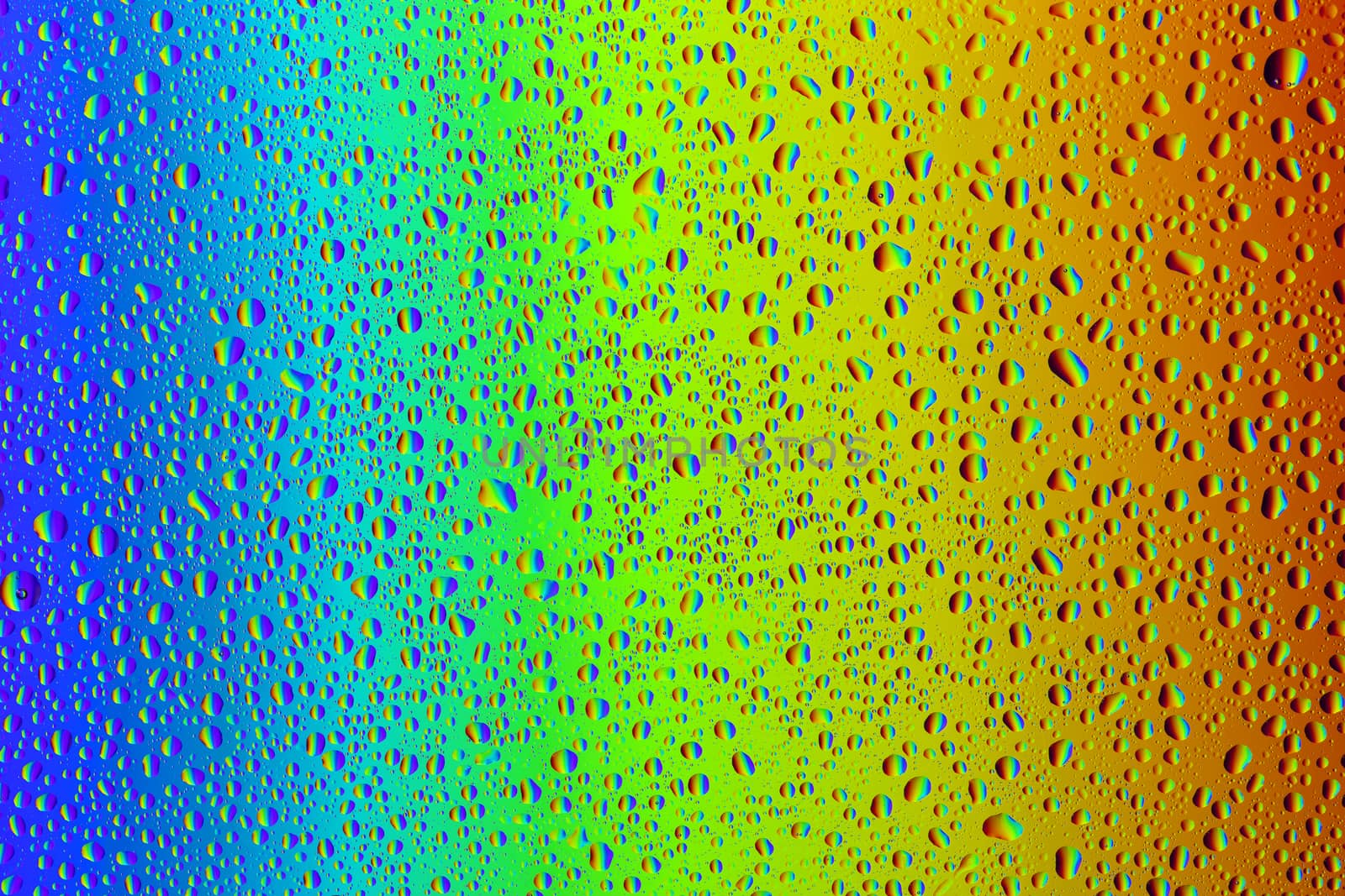 Drops of water against the background of the rainbow and with its reflection in them