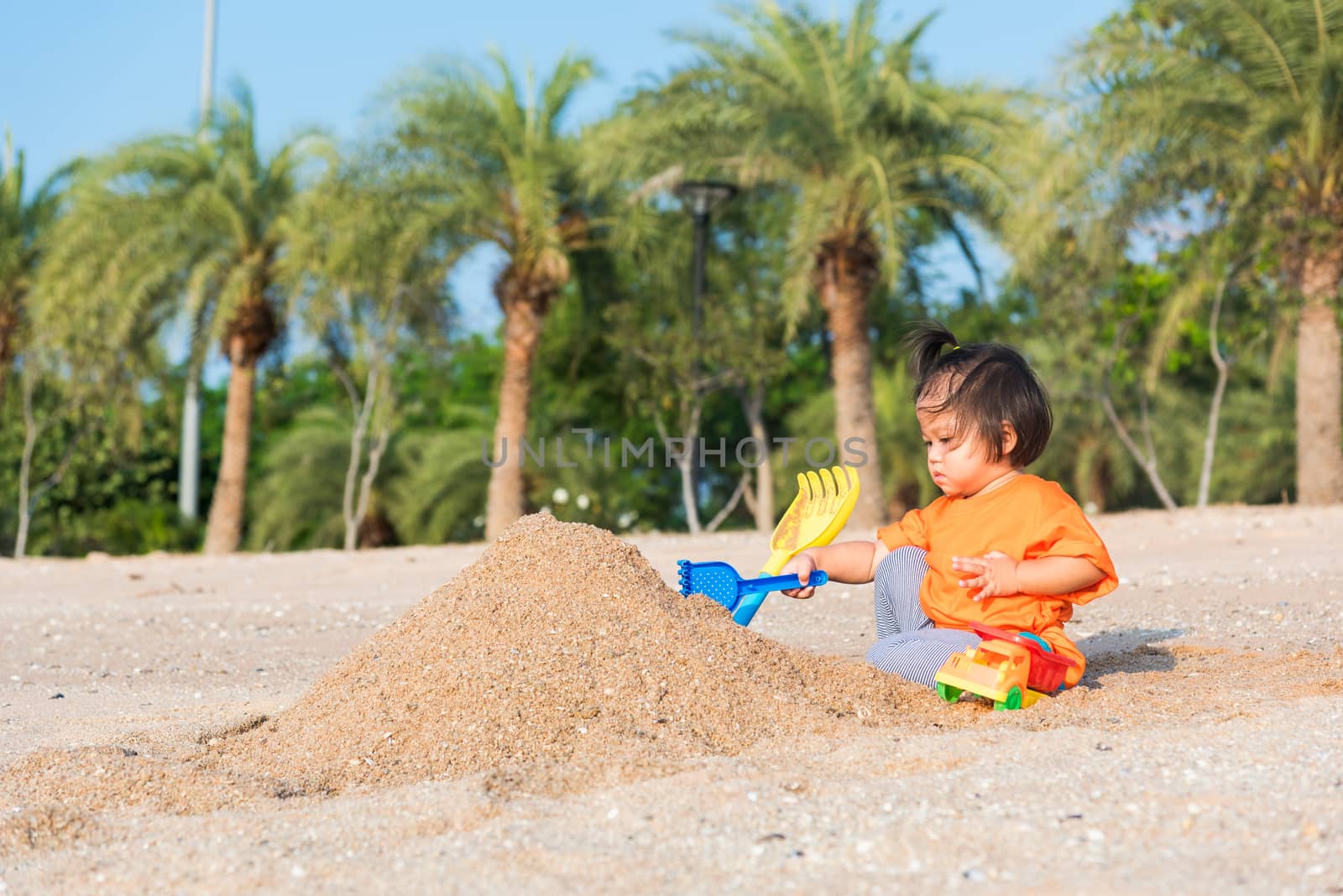 cheerful daughter girl funny digging playing toy with sand by Sorapop