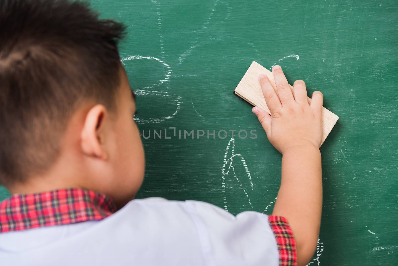 Child boy kindergarten in student uniform wiping clean or erase  by Sorapop