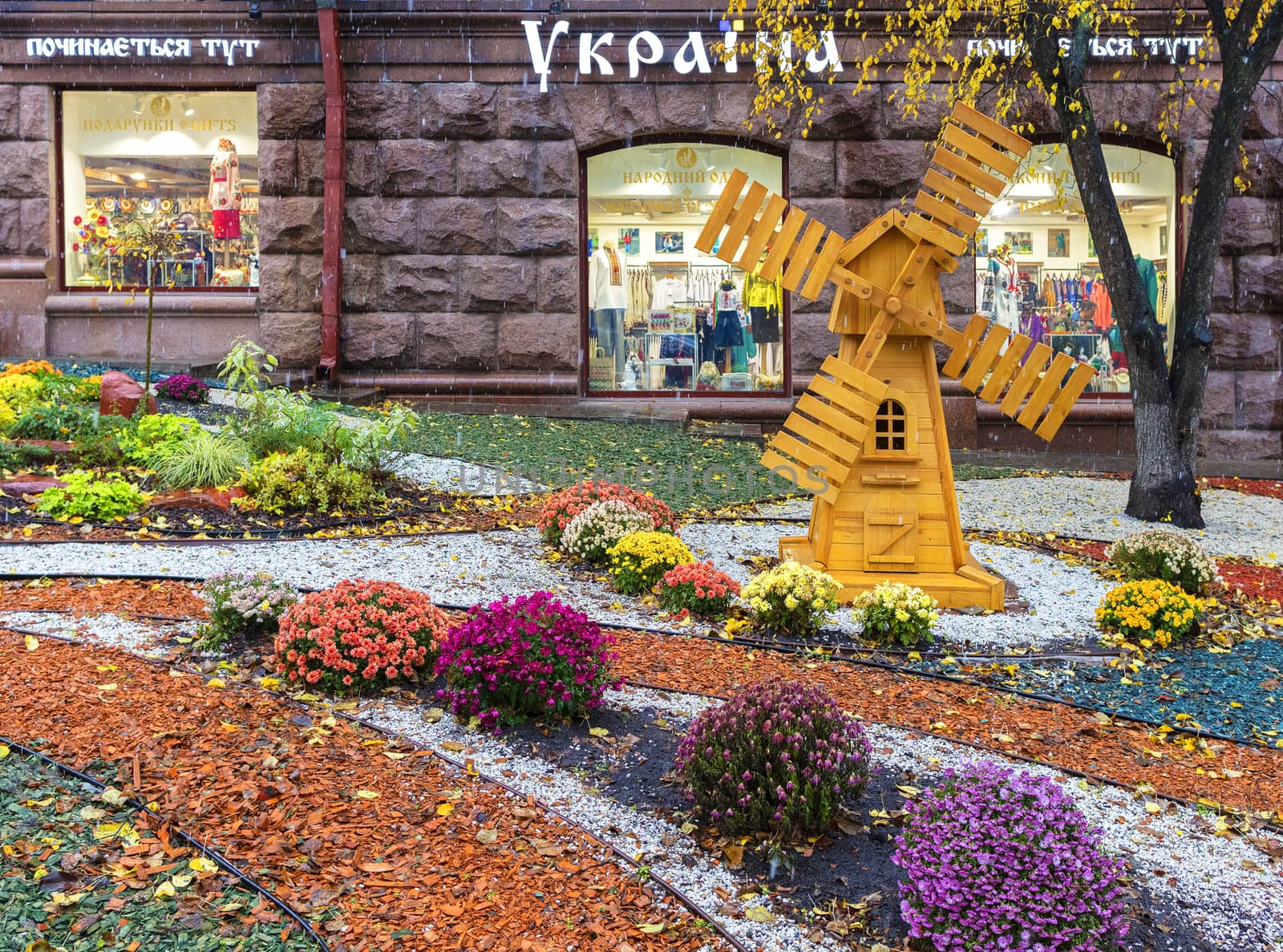 Kiev, Ukraine - October 2017: a flowerbed and wooden mill in front of the entrance to the store Ukraine in the center of Kiev