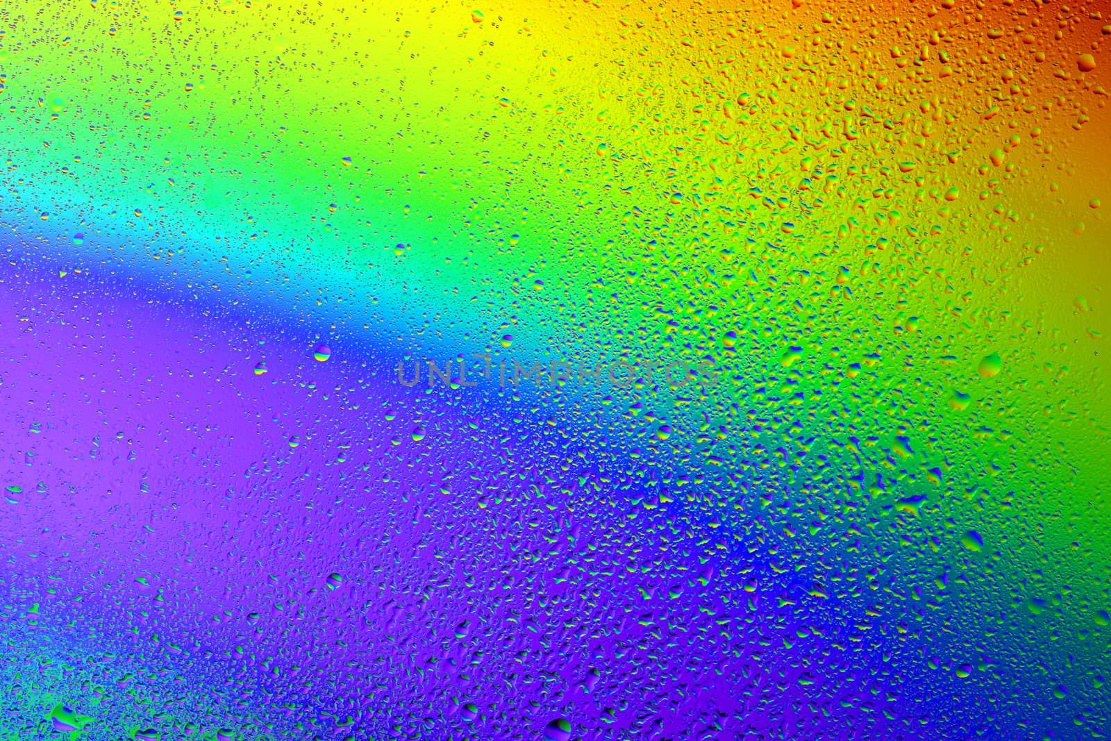Drops of water against the background of the rainbow and with its reflection in them