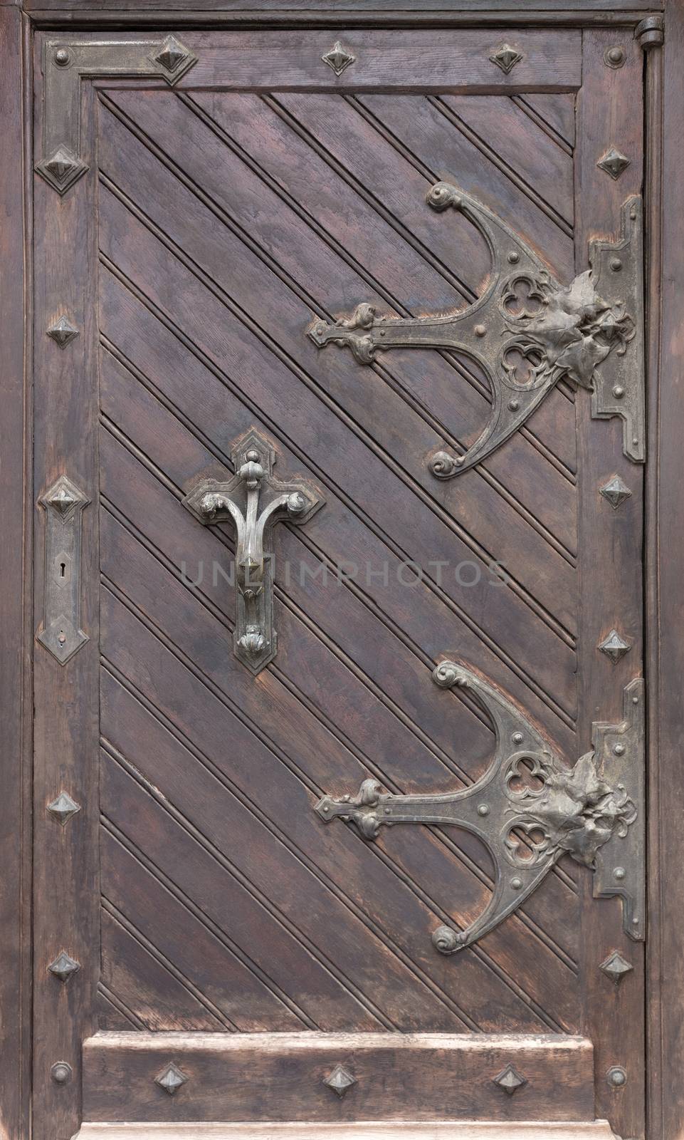 Ancient antique wooden doors with wrought iron loops and cross bars. by Sergii