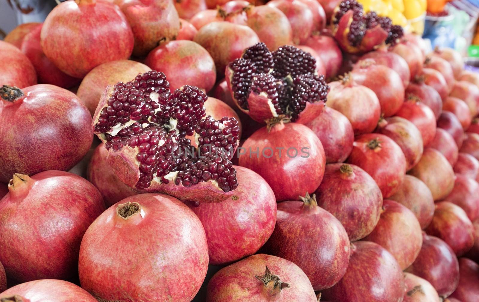 Ripe and red fruit pomegranate and divided into four parts, against the background of pomegranate fruit lined in rows