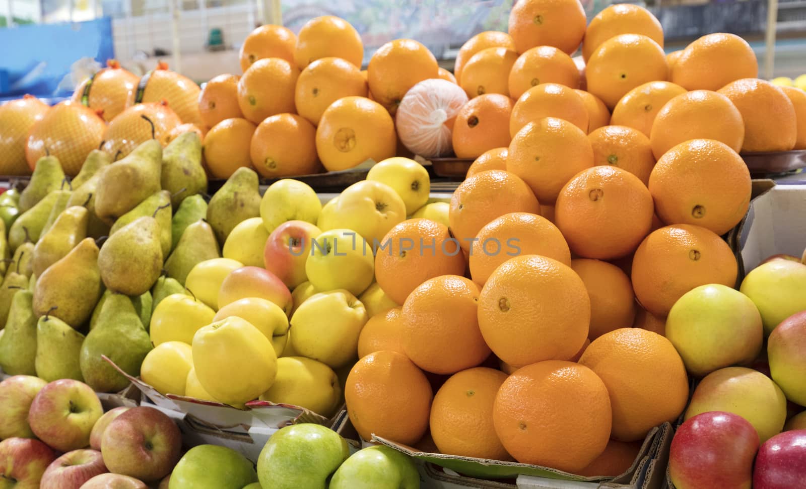 Bright background of fresh fruits. Oranges, apples, pears lie in the trays in the market and attract attention.