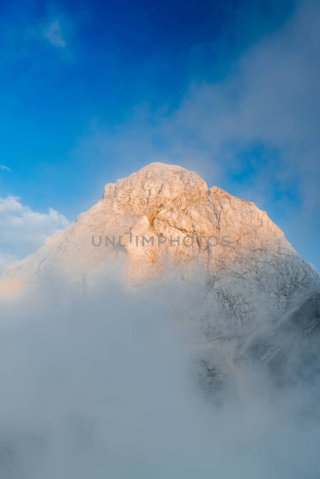 Sunset Illuminated Mangart Mountain Peak Above Clouds, Slovenia.