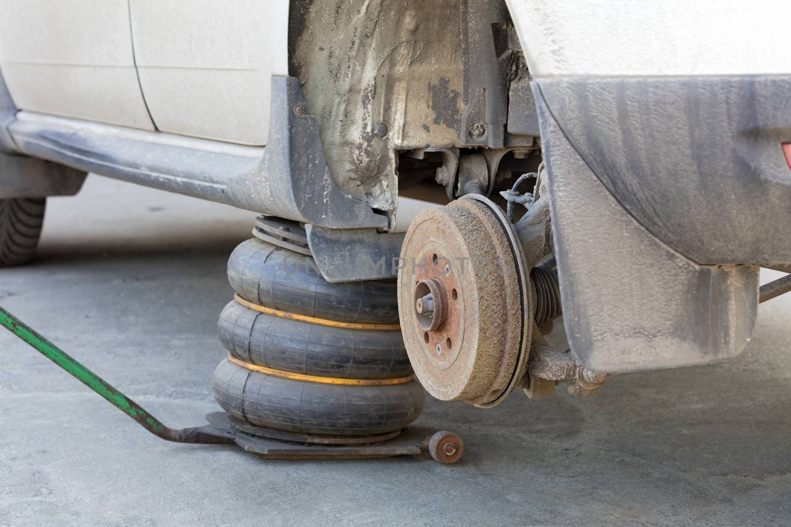 Worn disc brake on the car, as the new tire is replaced. Repair of automobile brakes in a car-care center.