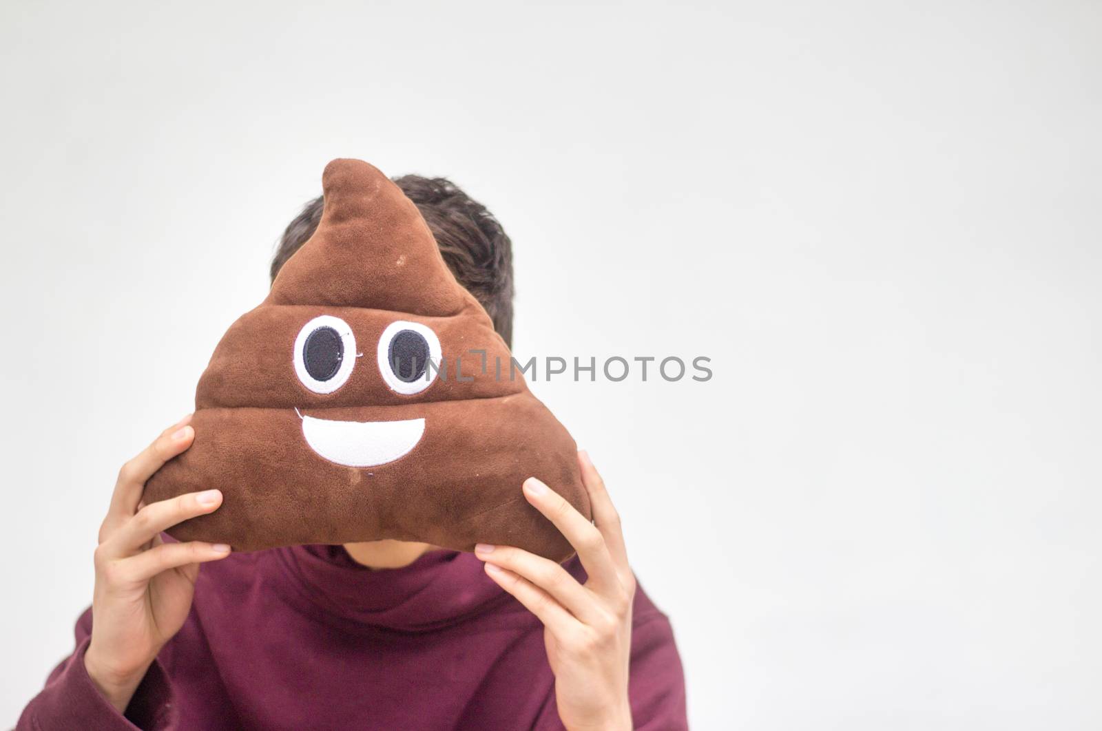 Photograph of a man with poop emoji cushion