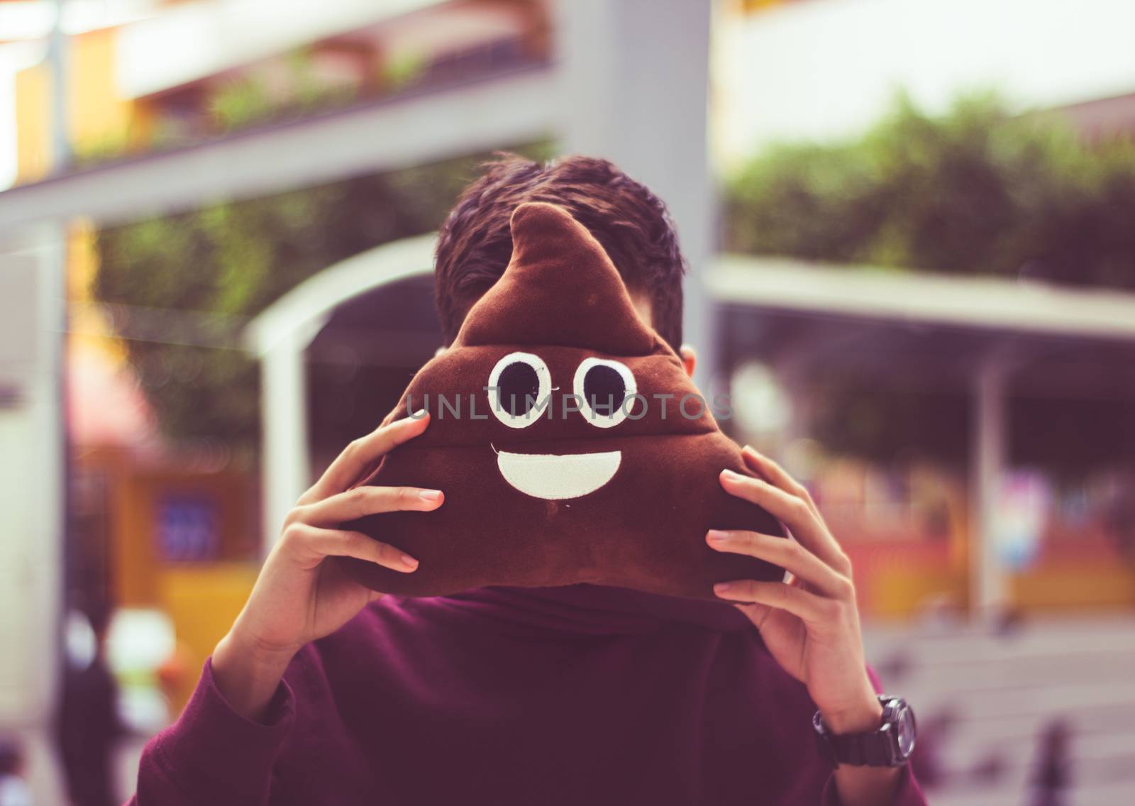 Photograph of a man with poop emoji cushion