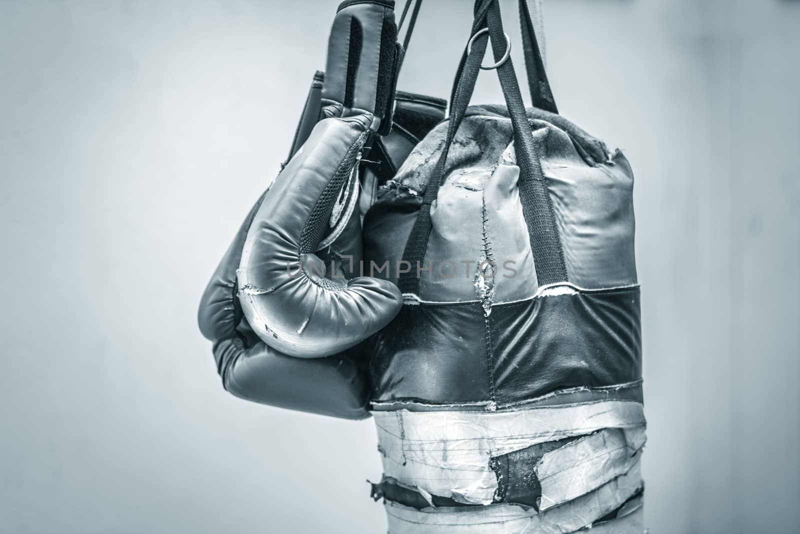 Photograph of an old punching bag and a pair of boxing gloves