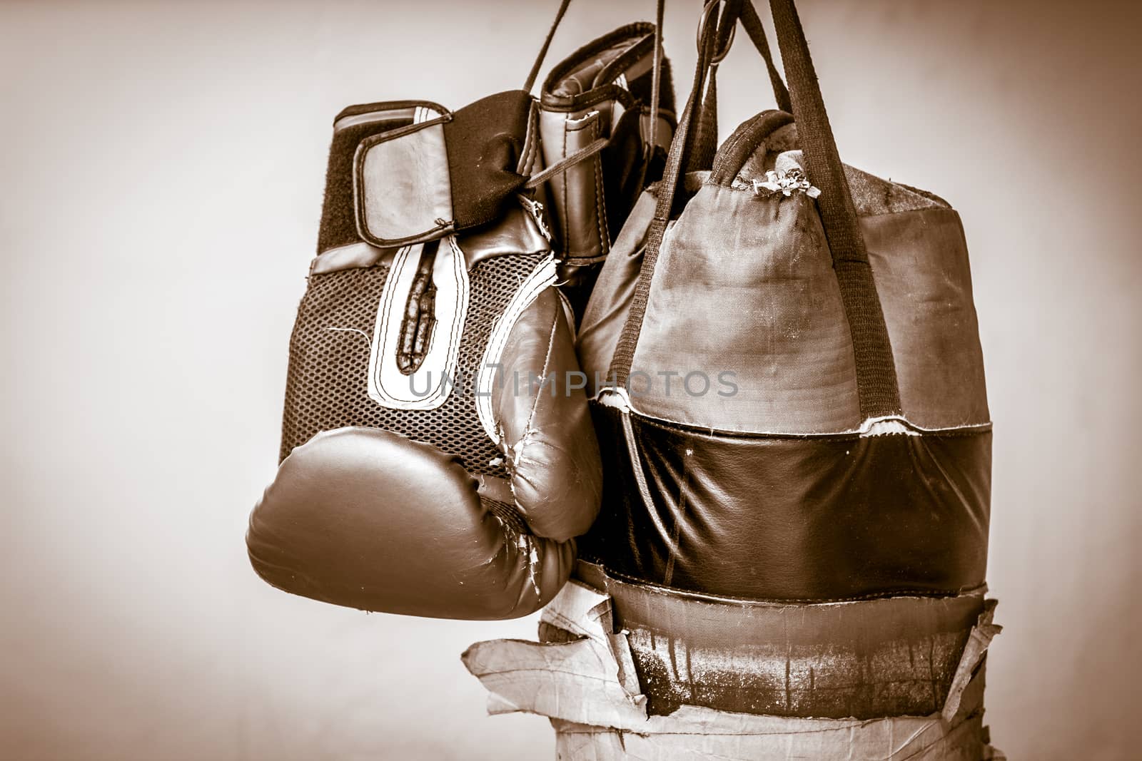 Photograph of an old punching bag and a pair of boxing gloves