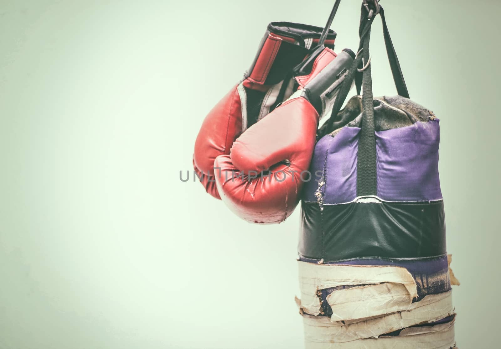 Photograph of an old punching bag and a pair of boxing gloves